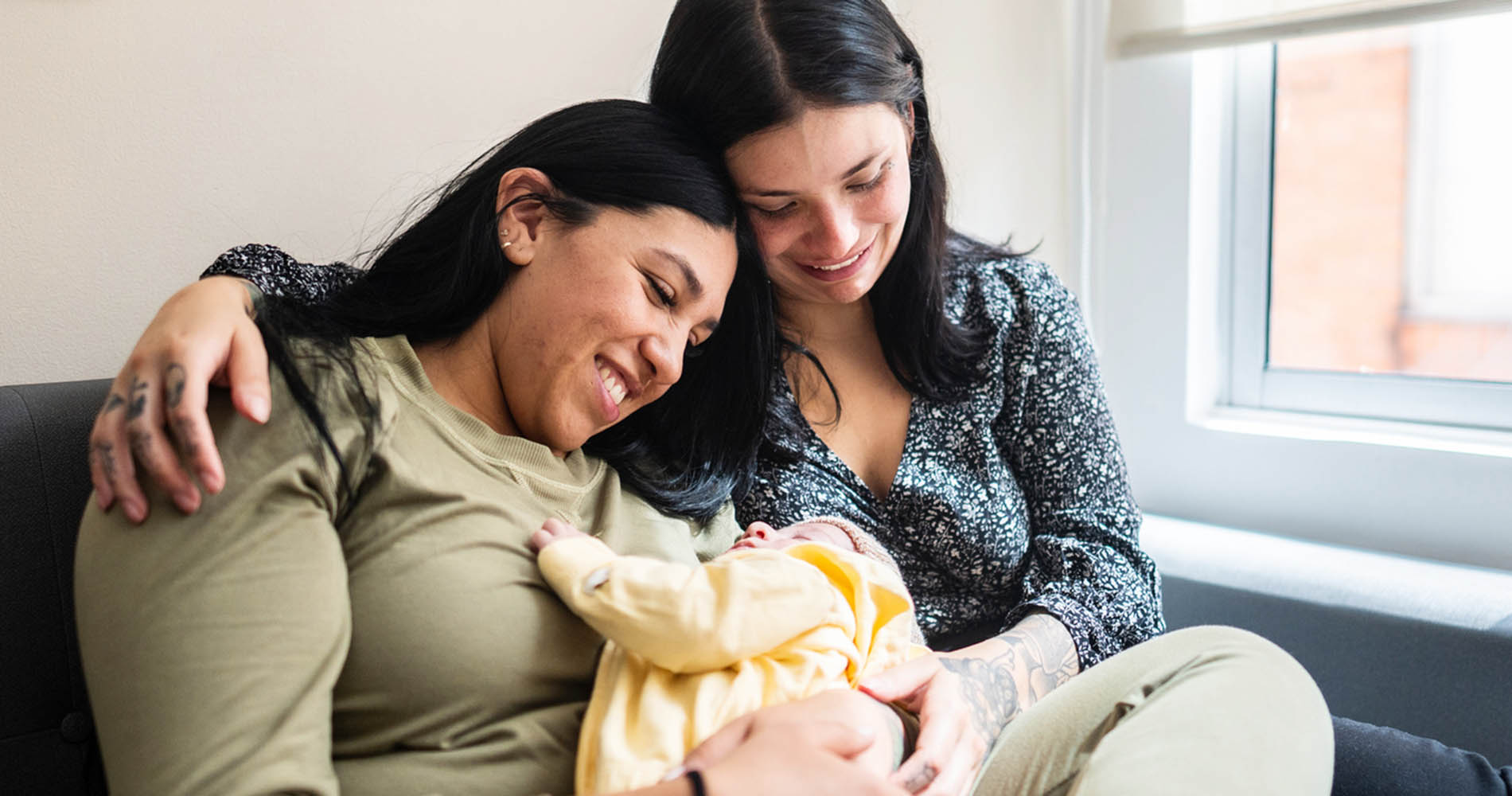 Lesbian couple embracing with son on lap at home